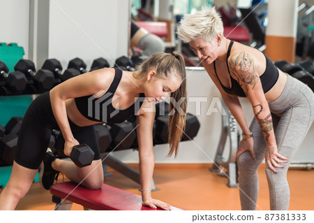 A young woman is doing fitness with a trainer at the GYM 87381333