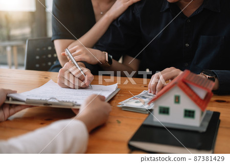 Real estate agent offer hand for customer sign agreement contract signature for buy or sell house. Happy asian couple signing a contract together at office. Real estate contact agreement concept 87381429