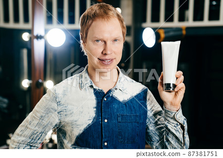 hairdresser and stylist barbershop worker with with tube of hair care products 87381751