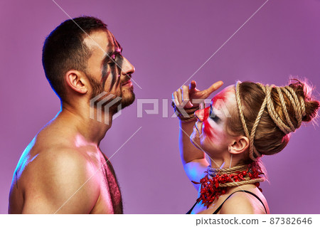 Beautiful young acrobats or gymnasts with colorful face painting on pink blue gradient background. Professional ballet couple dancing, Emotional duet performing choreographic art. Animal instinct Beautiful young acrobats or gymnasts with colorful face painting on pink blue gradient background. Professional ballet couple dancing, Emotional duet performing choreographic art. Animal instinct 87382646