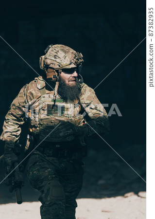 A bearded soldier in uniform of special forces in a dangerous military action in a dangerous enemy area. Selective focus  87382935