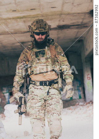 A bearded soldier in a special forces uniform walks through an abandoned building after a successful mission. Selection focus A bearded soldier in a special forces uniform walks through an abandoned building after a successful mission. Selection focus 87382992