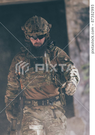 A bearded soldier in a special forces uniform walks through an abandoned building after a successful mission. Selection focus A bearded soldier in a special forces uniform walks through an abandoned building after a successful mission. Selection focus 87382993