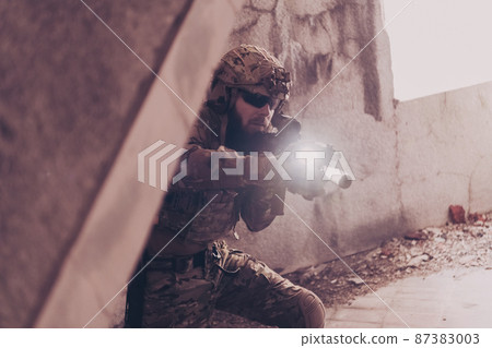 A bearded soldier in uniform of special forces in a dangerous military action in a dangerous enemy area. Selective focus  87383003