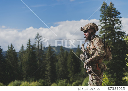 War concept. A bearded soldier in a special forces uniform fighting an enemy in a forest area. Selective focus War concept. A bearded soldier in a special forces uniform fighting an enemy in a forest area. Selective focus 87383015