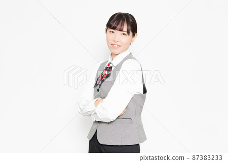 A smiling business woman standing in front of a white background with her arms folded A smiling business woman standing in front of a white background with her arms folded 87383233