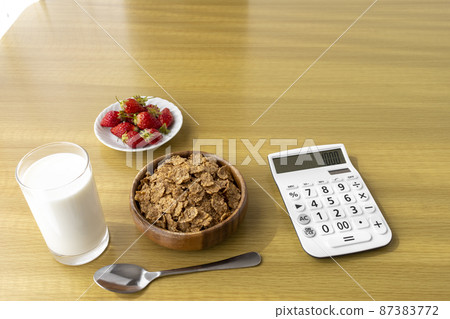 Calculator and breakfast (flakes, strawberries, milk). Image of food expenses 87383772