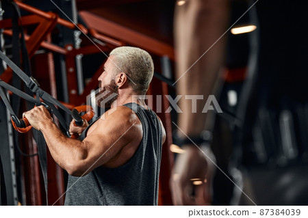 A man trains his arms and chest in the gym on the simulator, does exercises for different muscle groups. Fintes motivation, sports lifestyle, health, athletic body, body positive. Film grain. A man trains his arms and chest in the gym on the simulator, does exercises for different muscle groups. Fintes motivation, sports lifestyle, health, athletic body, body positive. Film grain. 87384039
