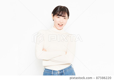 A smiling woman standing in front of a white background with her arms folded 87386220