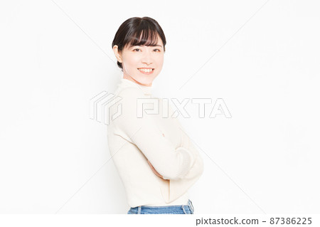 一個微笑的女人站在白色背景前,雙臂交叉 一個微笑的女人站在白色背景前,雙臂交叉 87386225