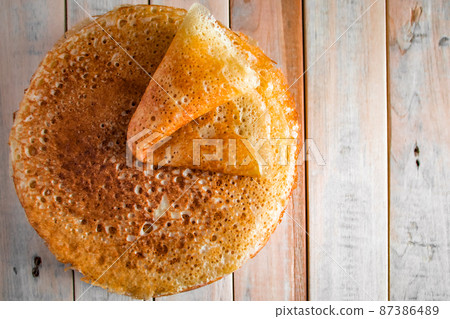 Appetizing thin pancakes on a wooden background. Russian food for the holiday Maslenitsa. Top view, place for text. 87386489