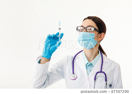 A nurse holds a syringe before giving an injection. The concept of vaccination. 87387290