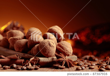 Chocolate truffles with cinnamon, anise, and coffee beans on a wooden table. 87387916
