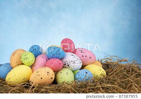 Colorful easter eggs on dry grass on sky blue background Colorful easter eggs on dry grass on sky blue background 87387955