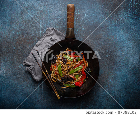 Asian stir fry noodles with vegetables in black wok pan 87388102