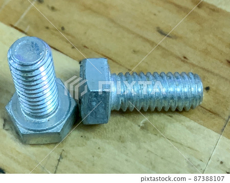 metal sliver bolts laying on wooden desk 87388107