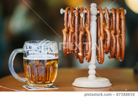 Close up salted soft pretzels and beer on wooden background. 87388658