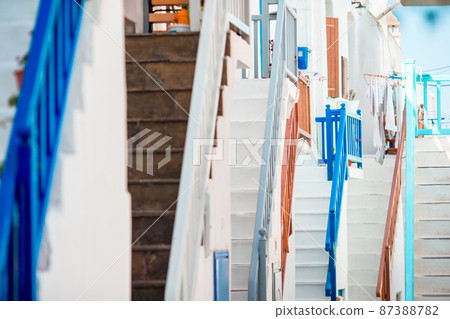 The narrow streets of the island with blue balconies, stairs and flowers. 87388782