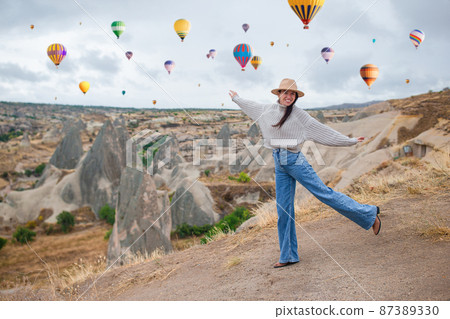 Happy young woman during sunrise watching hot air balloons in Cappadocia, Turkey Happy young woman during sunrise watching hot air balloons in Cappadocia, Turkey 87389330