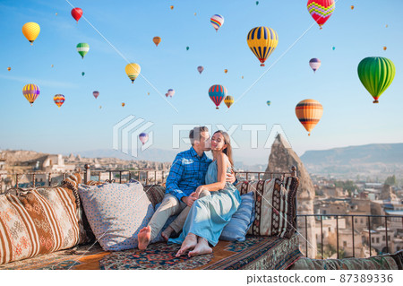 Happy young couple during sunrise watching hot air balloons in Cappadocia, Turkey Happy young couple during sunrise watching hot air balloons in Cappadocia, Turkey 87389336