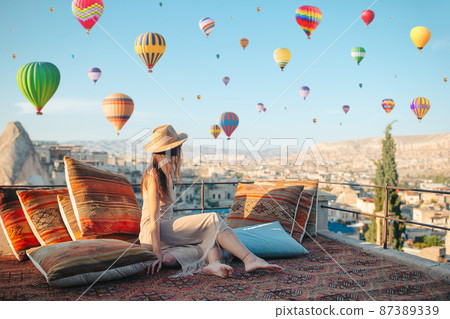 Happy young woman during sunrise watching hot air balloons in Cappadocia, Turkey 87389339