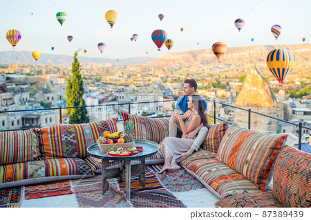 Happy young couple during sunrise watching hot air balloons in Cappadocia, Turkey 87389439