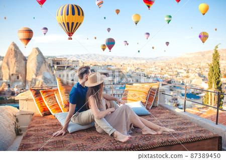 Happy young couple during sunrise watching hot air balloons in Cappadocia, Turkey Happy young couple during sunrise watching hot air balloons in Cappadocia, Turkey 87389450