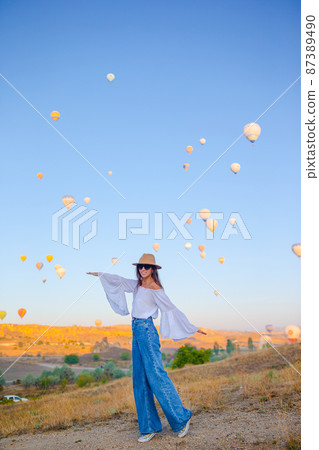Happy woman during sunrise watching hot air balloons in Cappadocia, Turkey Happy woman during sunrise watching hot air balloons in Cappadocia, Turkey 87389490