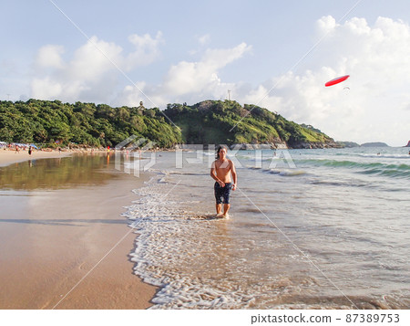 Man is playing with frisbee on Nai Harn beach on Phuket island. Leisure activity outdoors. Thailand. Man is playing with frisbee on Nai Harn beach on Phuket island. Leisure activity outdoors. Thailand. 87389753