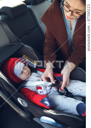 Infant sitting in baby car seat with safety belt locked protection 87390223