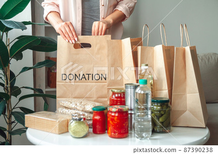 Woman packing food for donation in paper bag Woman packing food for donation in paper bag 87390238