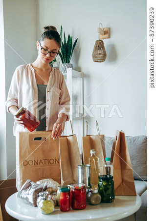 Woman packing food for donation in paper bag Woman packing food for donation in paper bag 87390239