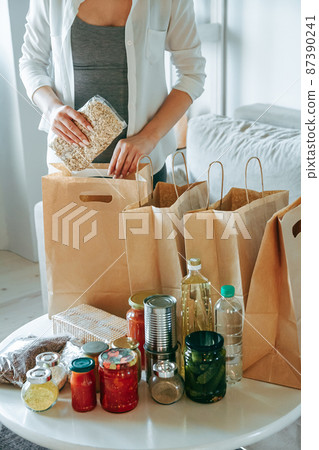 Woman packing food for donation in paper bag 87390241