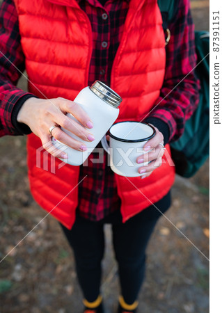 A girl pours hot tea from a thermos, a snack in the open air.Travel, trekking and hiking. 87391151
