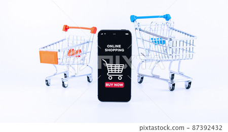 Online shopping. Digital smartphone with online shop application, shopping trolley on white background. Internet purchase, online shop concept. Website retail business. 87392432