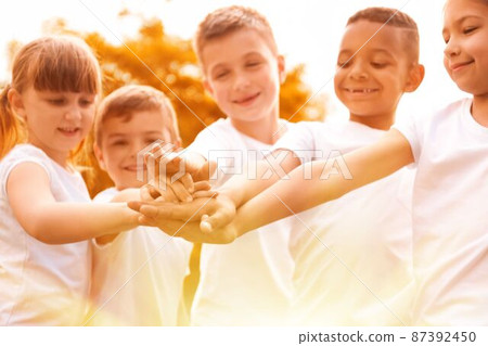 Group of children joining hands in park on sunny day. Volunteering with kids Group of children joining hands in park on sunny day. Volunteering with kids 87392450