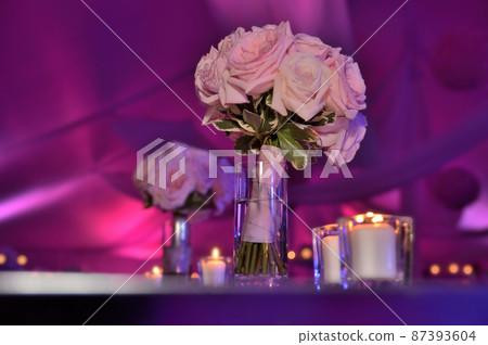 Beautiful wedding bouquet flowers on table at tent reception with pink and purple dramatic lighting 87393604
