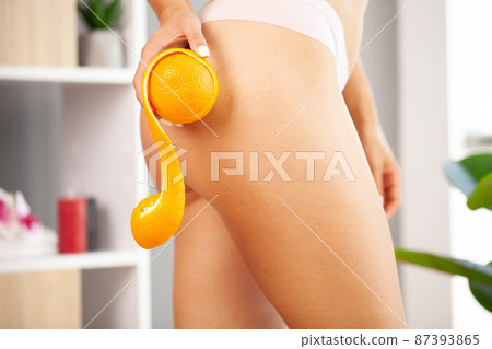 Cellulite problem, young woman holding orange near her leg 87393865