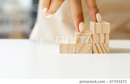 Women fingers climb up wooden block closeup 87393872