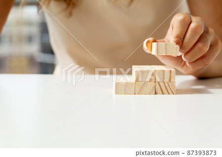 Female fingers climb ladder made of wooden blocks 87393873