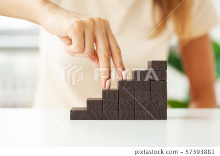 Women fingers climb up wooden block closeup 87393881