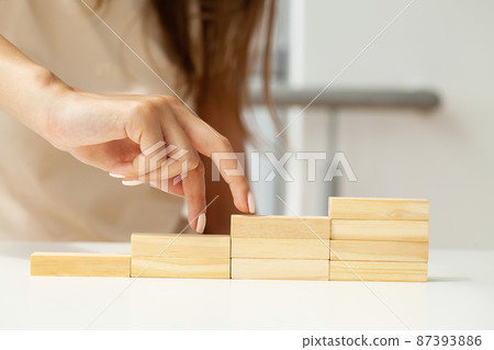 Women fingers climb up wooden block closeup 87393886