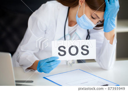 The doctor holds a form with the text sos The doctor holds a form with the text sos 87393949