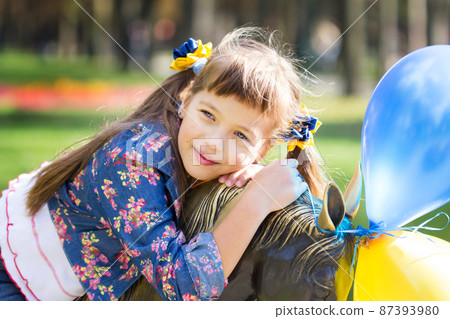 Flag Day of Independence of Ukraine. Stop WAR. Ukrainian girl in an embroidered vyshyvanka shirt with a yellow-blue flag of Ukraine. Symbols of the flag of Ukraine. Freedom. Russia terror. Kyiv.  87393980