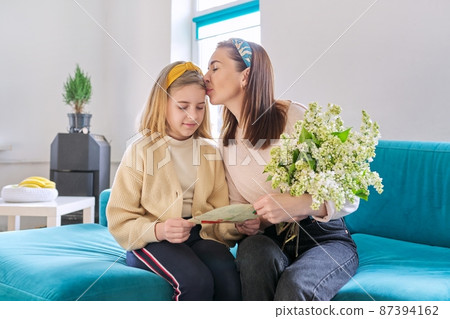 Happy mother and daughter child congratulating with bouquet of flowers and card Happy mother and daughter child congratulating with bouquet of flowers and card 87394162