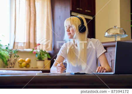 Teenage female student studying at home using a laptop. Teenage female student studying at home using a laptop. 87394172