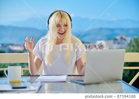 Teenage female student in headphones studying online, using laptop for video conference Teenage female student in headphones studying online, using laptop for video conference 87394180