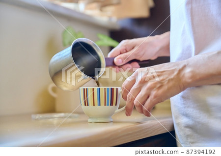 Close-up of a woman's hands preparing coffee in an iron cezve. Close-up of a woman's hands preparing coffee in an iron cezve. 87394192