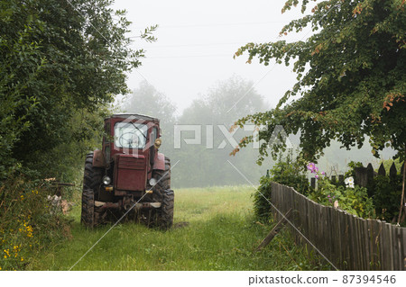 Old red tractor. Beautiful misty rural landscape. Old red tractor. Beautiful misty rural landscape. 87394546