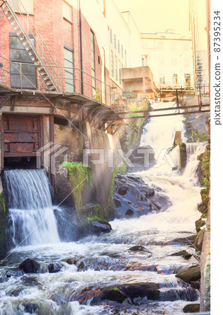 Kvarnbyn Waterfall in old industrial work area in Molndal, Gothenburg, Sweden, sun rays effect 87395234